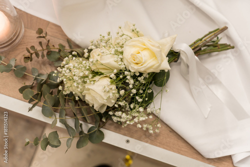 Elegant white roses arranged with baby’s breath and eucalyptus on a wooden table during a wedding setting in early evening light