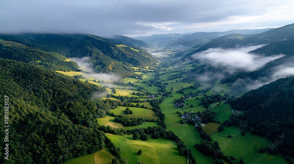 Fototapeta premium Stunning aerial view of green valleys and hills in a misty landscape during early morning