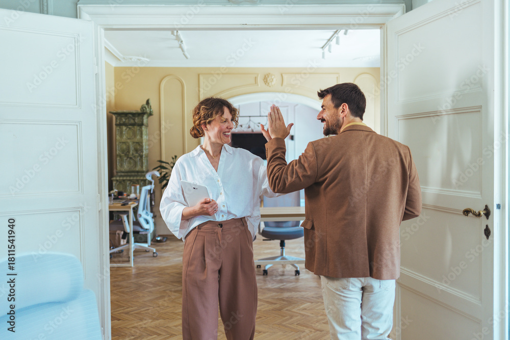 Obraz premium Casual Office High Five Between Colleagues Celebrating Success in a Bright Modern Workspace