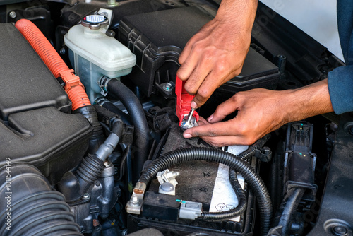 Bild auf Leinwand A mechanic replacing a car battery, tightening the terminal connection inside the engine bay