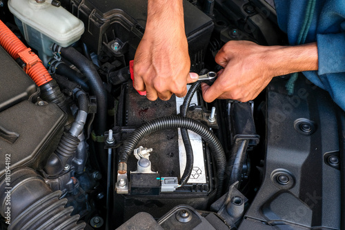 Foto A mechanic replacing a car battery, tightening the terminal connection inside the engine bay