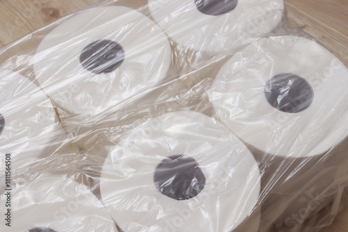 Close-up of multiple rolls of toilet paper wrapped in plastic, showcased on a wooden surface. Ideal for home supplies, hygiene concepts, and everyday necessities.