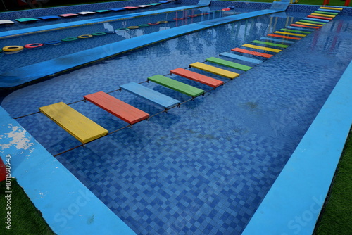 Colorful Wooden Stepping Stones Path Across a Refreshing Swimming Pool
