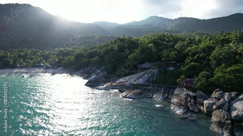 peaceful tropical shoreline with rugged stones, calm seaside with lush greenery and sparkling waters
