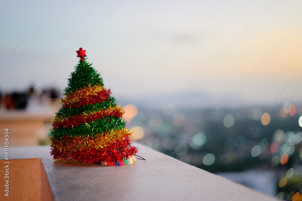 Obraz premium Festive Mini Christmas Tree Decorated With Colorful Tinsel On Balcony