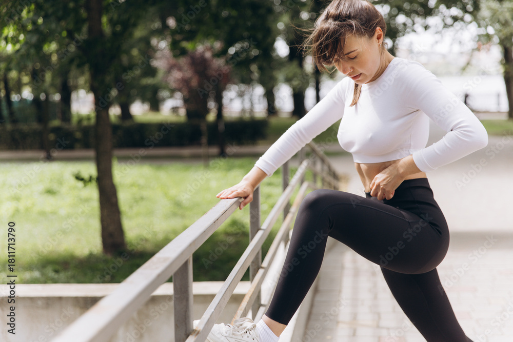 Naklejka premium Woman stretching leg outdoors, concentrating on workout