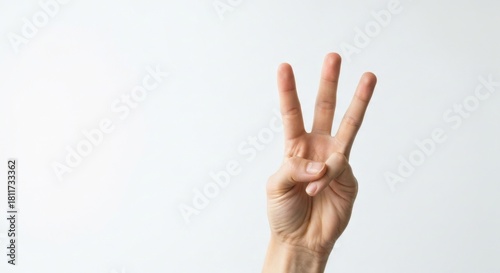 Hand gesturing a number three, three fingers are extended upwards
