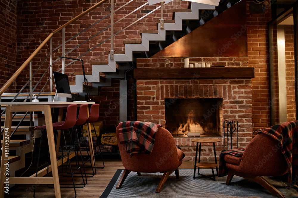 Obraz premium Modern business office interior featuring empty seating area with mid century style chairs and barstools arranged near brick fireplace and staircase, no people visible