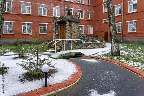 Fototapeta Naklejka Na Ścianę i Meble -  A small playground in front of a brick building covered in snow