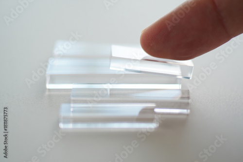 Clear Acrylic Blocks being Arranged by Finger on Light Background Indicating Transparency for Construction or Design Concept as Demonstration