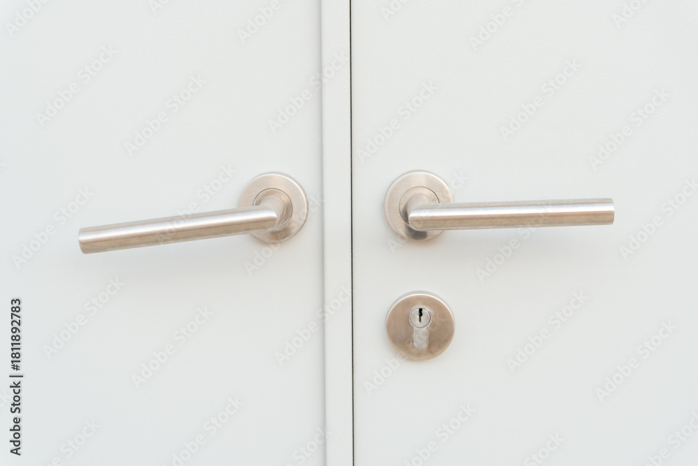 Obraz premium White door panel or door leaf with two silver door grips or handles and separated keyhole used as background