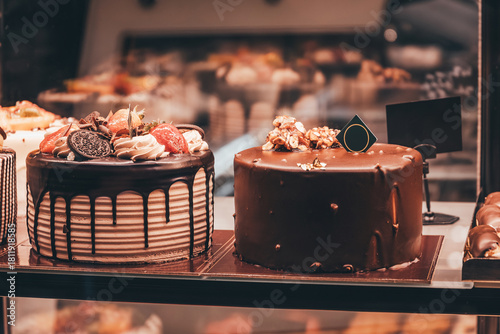 Fotografi Chocolate cakes decorated with fruits and nuts displayed behind