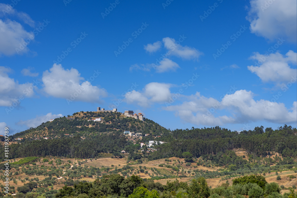 Obraz premium The medieval Ourém Castle (Castelo de Ourém) stands atop a lush green hill in the Santarém district, Portugal, overlooking a vast rural landscape.