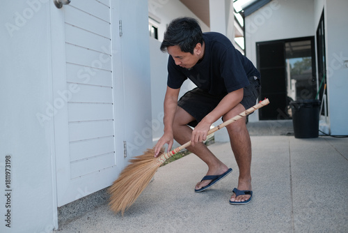 Tableau sur toile A man is sweeping the floor with a broom