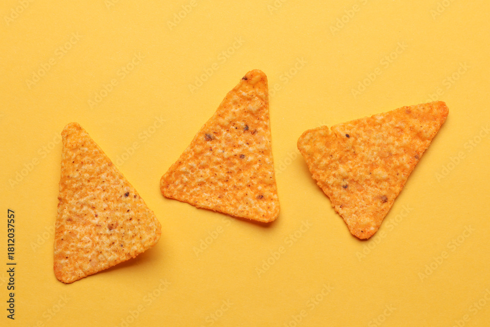 Fototapeta premium Triangular appetizing corn tortilla chips slices on yellow background