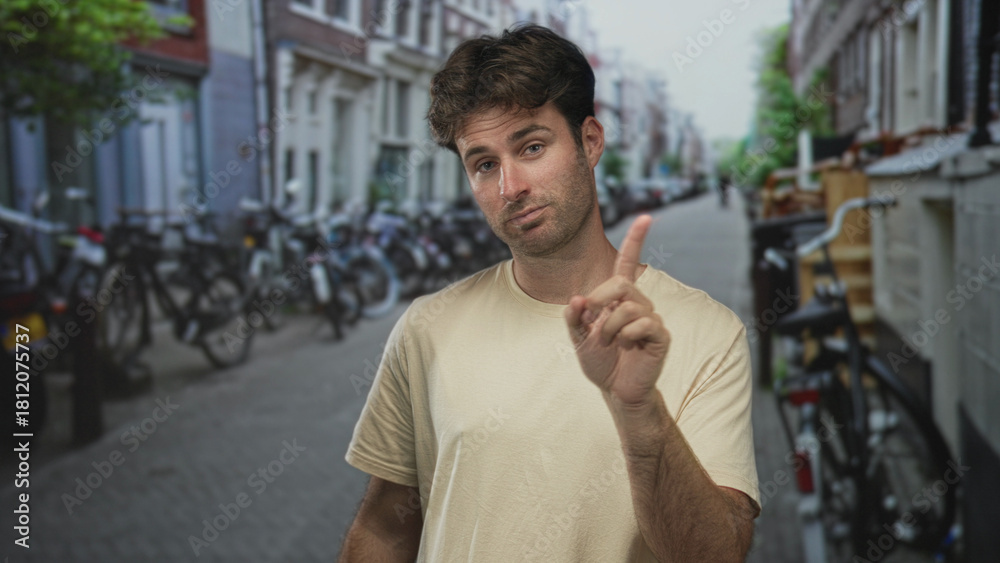 Fototapeta premium Man with finger to lips for silence on a city street framed by rows of parked bicycles and narrow buildings; hush.