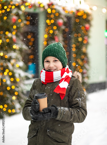 Happy child kid teen boy holding red mug of hot cocoa, chocolate or tea and drinking. Children activity in winter day. Holiday vacation concept.