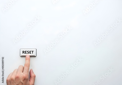 Finger pressing physical Reset button on white background with large copy space for fresh start concept
