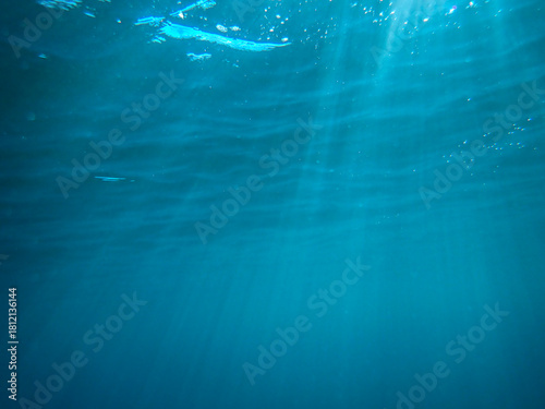Ocean underwater rays of light background, under blue water sunlight. Underwater background, ocean or sea surface seen from under water. Rays of light beams, abstract marine backdrop. Nature landscape