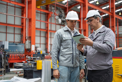 Foto Engineers inspecting equipment and discussing maintenance procedures inside a modern industrial factory