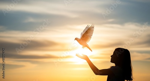 Silhouette of girl releasing white dove at sunset with glowing light bird flying