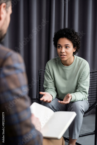 Young Female Candidate With Curly Hair Gesturing While Explaining To Recruiter During Casual Job Interview