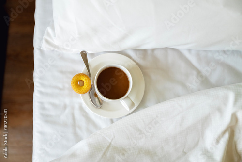 Cup of coffee on white sheets in the bed