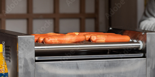 Fototapeta Naklejka Na Ścianę i Meble -  Hot dogs cooking on roller grill at street food vendor