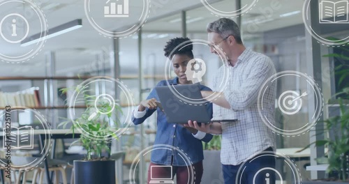 Woman tapping laptop screen causing UI icons and charts, man pointing and guiding business review