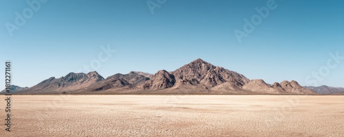 Desert mountain range under clear blue sky with wide dry ground surface, ideal for nature backgrounds, travel banners, and landscape design