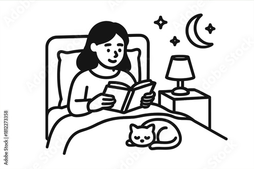 Young woman reading a book in bed at night with a sleeping cat and bedside lamp