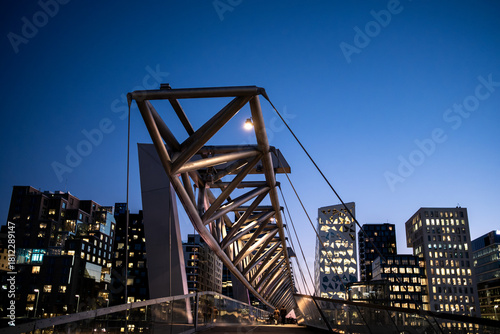 Architecture cityscape at night showing Barcode Oslo skyline behind bridge structure and lights that combine to form a dynamic and recognizable urban scene.