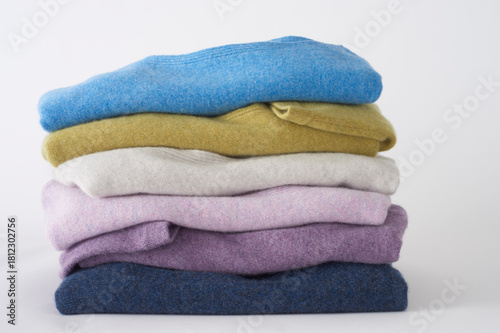 Stack of colorful cashmere sweaters folded neatly on white background