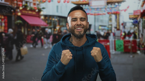 Wallpaper Mural Man smiling with clenched fists on a busy street lined with shops and lanterns; joy celebration confidence. Torontodigital.ca