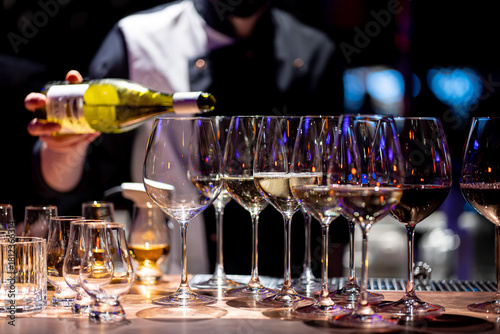 Waiter pouring wine into wineglass. Waiter work. Sommelier pours alcoholic drink