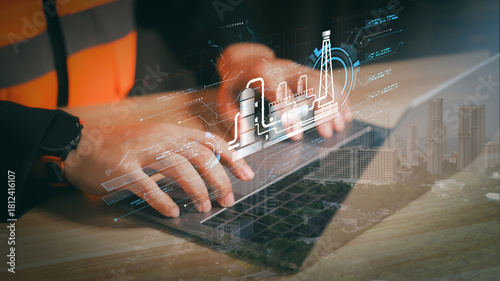 Engineer using laptop with holographic oil refinery plant overlay. Concept of smart factory automation technology, future energy innovation, and industrial digital transformation.