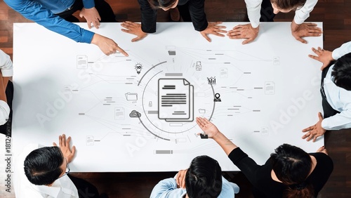 Fotografi A diverse team engages in a collaborative business meeting, analyzing project workflow on a table filled with documents, ideas, and technology icons