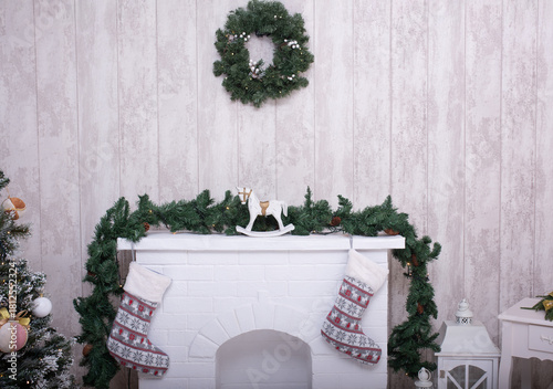 Photography Cozy holiday fireplace adorned with festive stockings, evergreen garland, and a