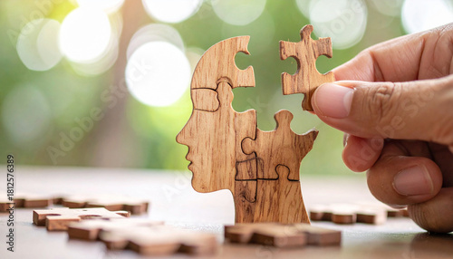 Hand Placing Final Piece in Wooden Head Puzzle Portraying Mental Health Solutions and Cognitive Growth