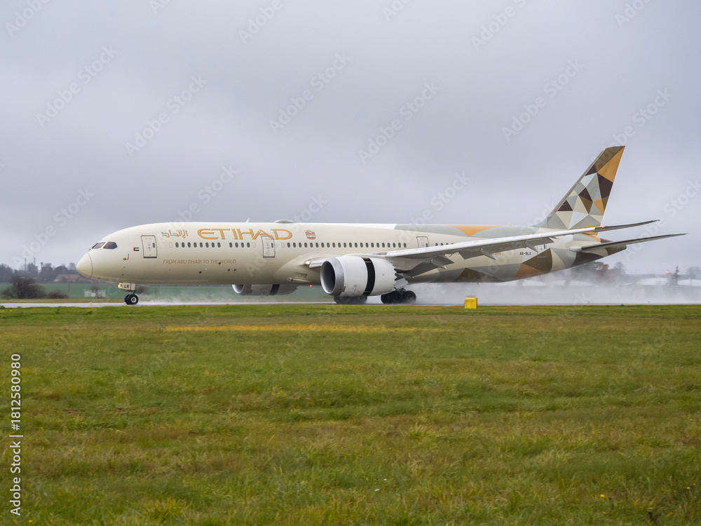 Fototapeta premium PRAGUE, Czech Republic - November 17, 2025: Etihad Airways Boeing 787-9 Dreamliner (A6-BLK) taxiing on a wet runway with water spray.