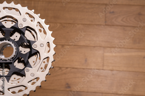 Close-up of a multi-sprocket rear cassette mounted on a bicycle hub, partially visible on wood background