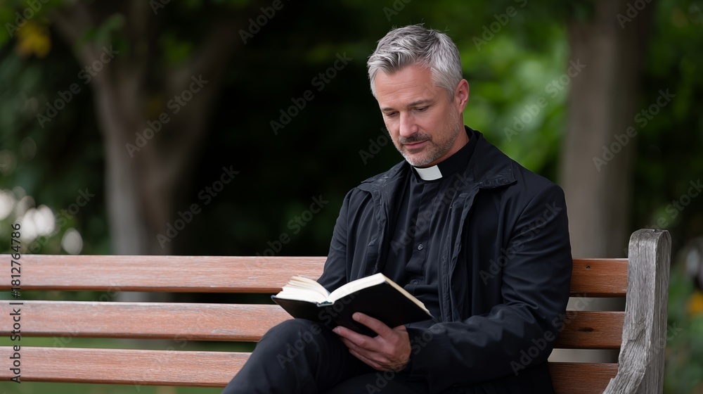 Obraz premium Priest studying book on park bench in shaded outdoor setting