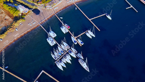 Thin pier bridges with moored pleasure yachts and catamarans on the calm waters of the sea coast 
