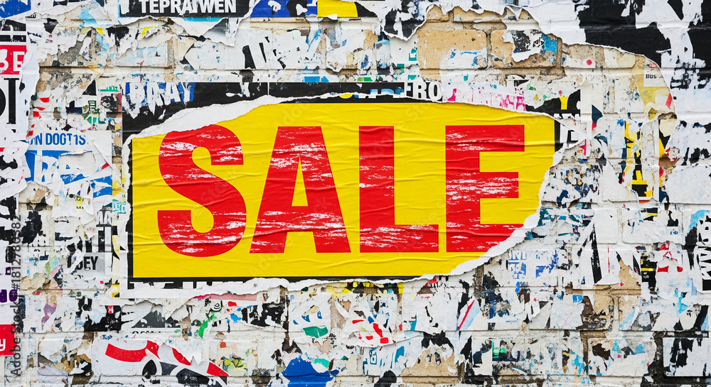 Fototapeta premium Torn posters on brick wall, revealing the word SALE on a yellow background, representing retail discount and commercial promotion for consumerism