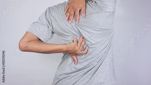 Back pain. A young man with back pain is touching and massaging his upper back. His shoulders are stiff and painful. Back injury, muscle pain, fatigue, health problems
