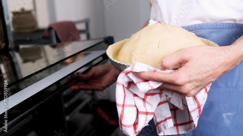 Woman hands placing raw apple pie in oven at home kitchen – Holiday baking, small business, traditional dessert concept