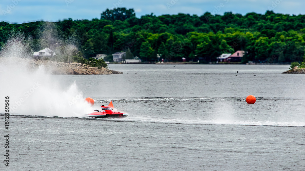 Fototapeta premium Red and white racing boat speeding around two orange bouys
