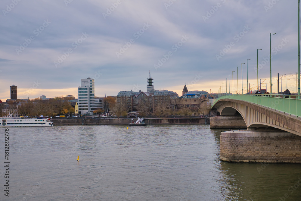 Fototapeta premium View of riverside buildings and bridge in a city during overcast evening hours