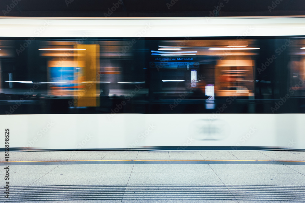 Fototapeta premium A high-speed metro train captured with strong motion blur as it passes through an urban station in Budapest, Hungary