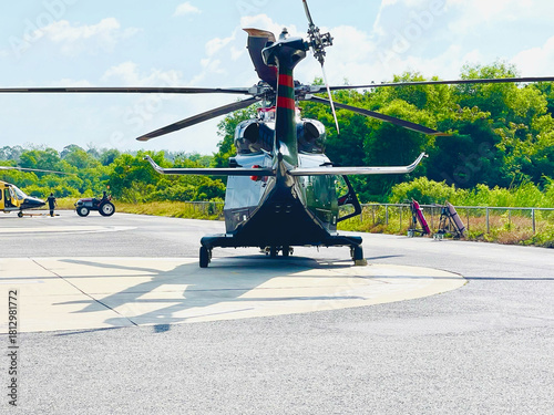 Helicopter Parked on Helipad with Green Forest Background